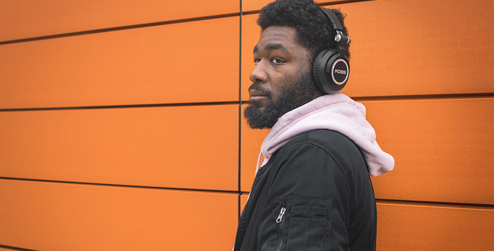 Photo of Ace Parker against a orange wall wearing the Koss BT540i Headphones..