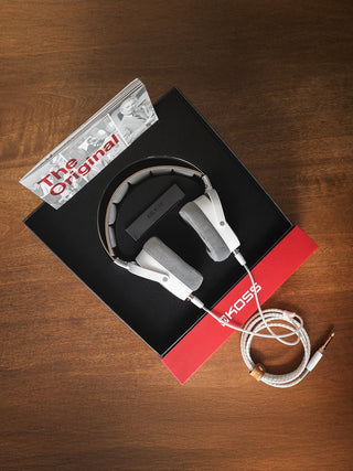 The Koss A/550 headphones inside of it's packaging laying on a desk showing the headphone and included booklet.