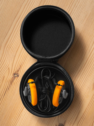 Black case with orange earplugs on a wooden surface