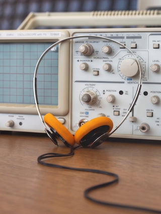 Headphones on an oscilloscope with a wooden surface background