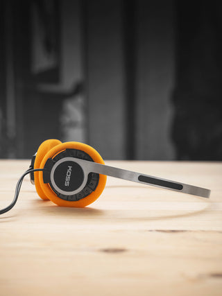 Orange and black headphones on a wooden surface with a blurred background