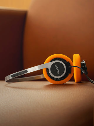 Orange and silver headphones on a brown surface