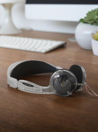 Headphones on a wooden desk with a computer keyboard and decor in the background