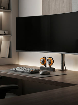 Modern office desk setup with a large monitor, keyboard, mouse, and speakers.