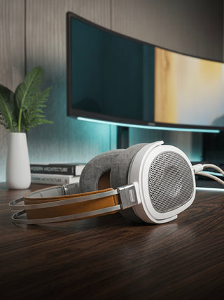 Headphones on a desk with a computer monitor in the background