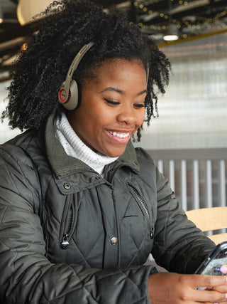 Women wearing Koss KPH30 Wireless in a cafe using a smartphone to listen to music