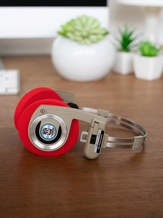 Koss Porta Pro Wireless Rhythm Beige laying on a desk with Red Oversized Cushions