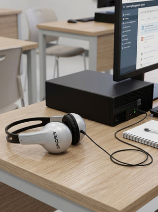 White and black headphones on a desk with a computer monitor in the background