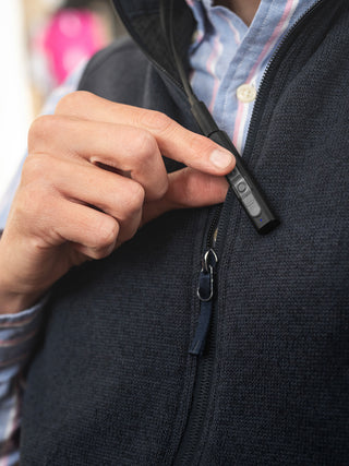 Person zipping a black jacket with a device attached to the zipper.